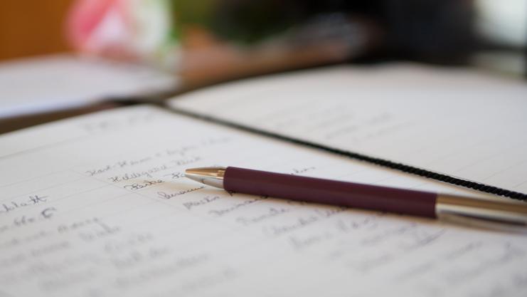 Nahaufnahme eines offenen Notizbuchs mit handschriftlichen Notizen und einem Kugelschreiber auf einem Tisch.